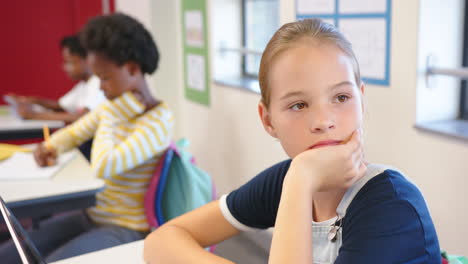 in school, girl sitting at desk looking thoughtful in classroom