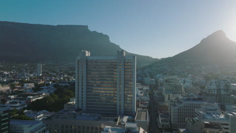 High-rise-building-in-city.-Forwards-fly-above-urban-borough.-Mountains-in-background.-Cape-Town,-South-Africa