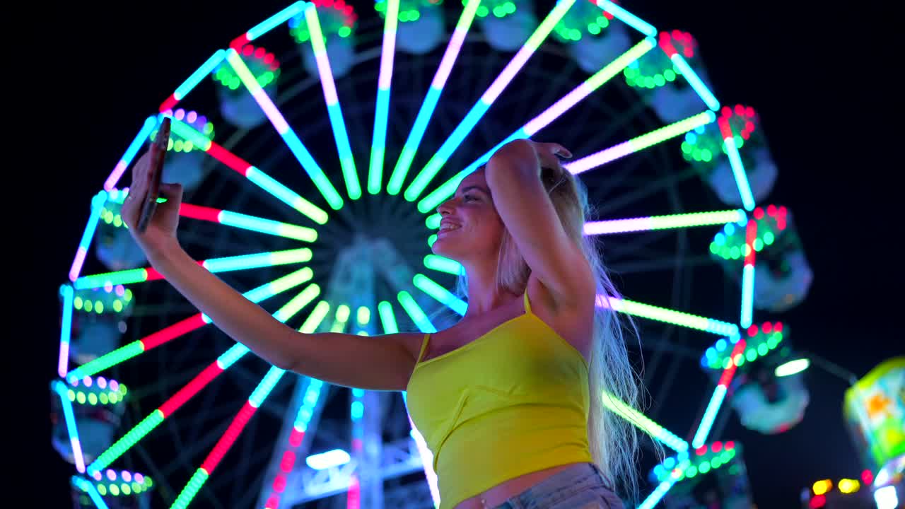 Woman taking a selfie at a carnival with a ferris wheel in the background