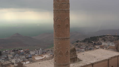 La-Cámara-Inclina-El-Minarete-Histórico-De-La-Mezquita-Mardin-Ulu,-Hecho-De-Piedra-Cortada,-De-Arriba-A-Abajo