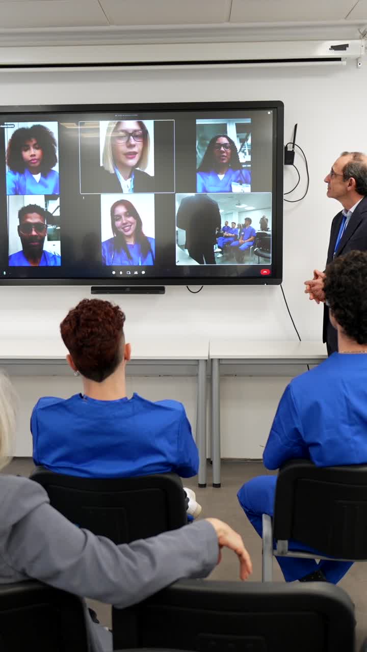 Estudiantes y profesionales viendo una videoconferencia en un aula