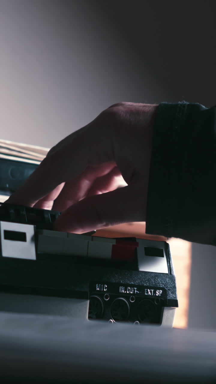 Primo piano verticale di una mano che inserisce una cassetta in un registratore audio retrò. Ideale per nostalgia della tecnologia, interviste, indagini di polizia, documentari sul crimine, giornalismo