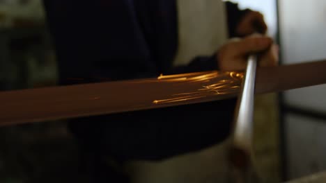 metalsmith sharpening metal rod in workshop 4k