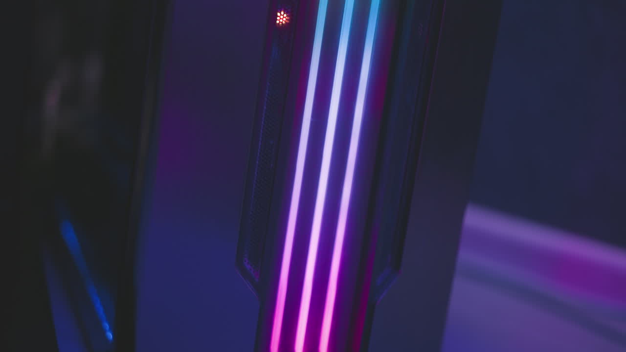 Close up of speaker system with glowing vertical LED stripes in green and yellow tones, placed in dimly lit tech room with colorful reflections and modern lighting ambiance