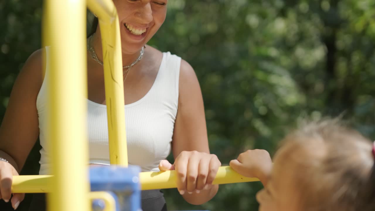 임신 한 어머니 와 딸 이 야외 체육관 에서 운동 하고 있다