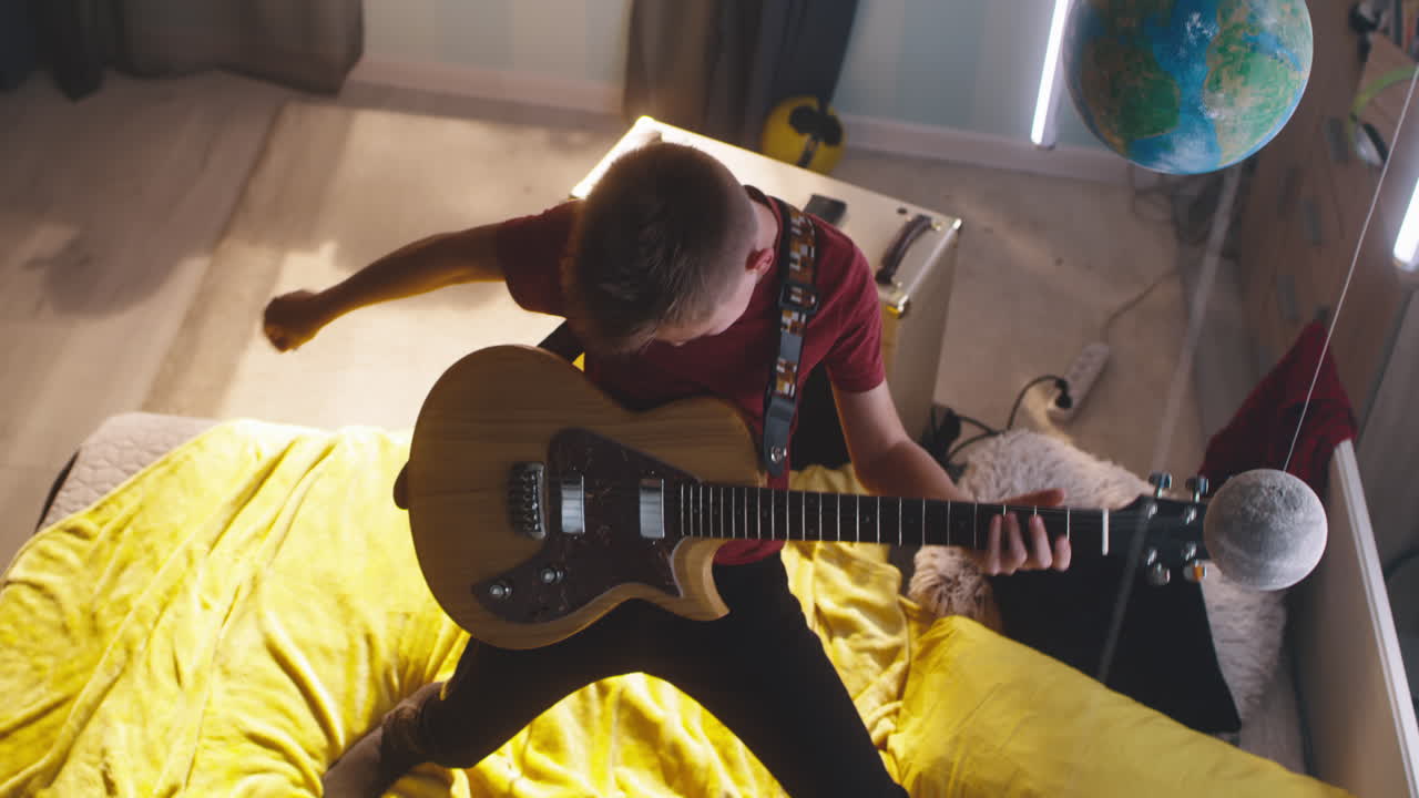 Teenage boy playing electric guitar in his bedroom