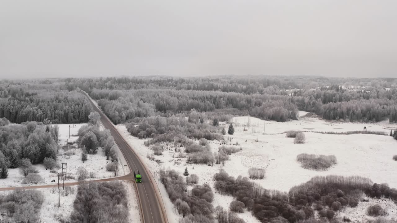 Aerial view of a two lane highway in countryside with truck passing by on a cloudy winter day. Frost over the landscape.