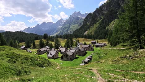 traditional alpine houses in crampiolo sit among meadows and peaks in alpe devero, piedmont, italy, under a sunny summer sky