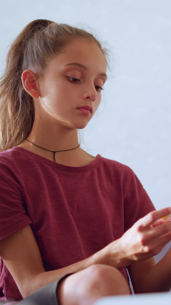 Little girl seated with crossed leg on couch carefully checks thermometer used by her brother sitting next to her showing concern and responsibility in soft natural indoor light expressing sibling care