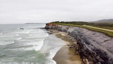 stunning aerial footage sweeping along dramatic cliffs and a vibrant beach with crashing waves