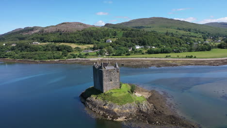 Beeindruckende-Drohnenaufnahme-Von-Castle-Stalker,-Schottland,-Die-An-Einem-Spektakulären-Sommertag-Von-Oben-Um-Die-Burg-Herumfegt