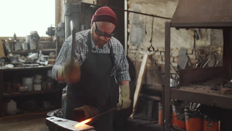 blacksmith forging metal with hammer on anvil