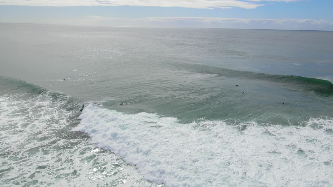 surfista montando las grandes olas del océano sobre el paisaje nublado del cielo azul en la playa del parque nacional burleigh heads en australia