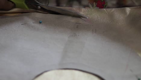 tela cortada lenta y rotundamente con una tijera de color aluminio sobre la mesa por la mano femenina del sur de asia mientras la cámara se mueve con el clip de movimiento b roll