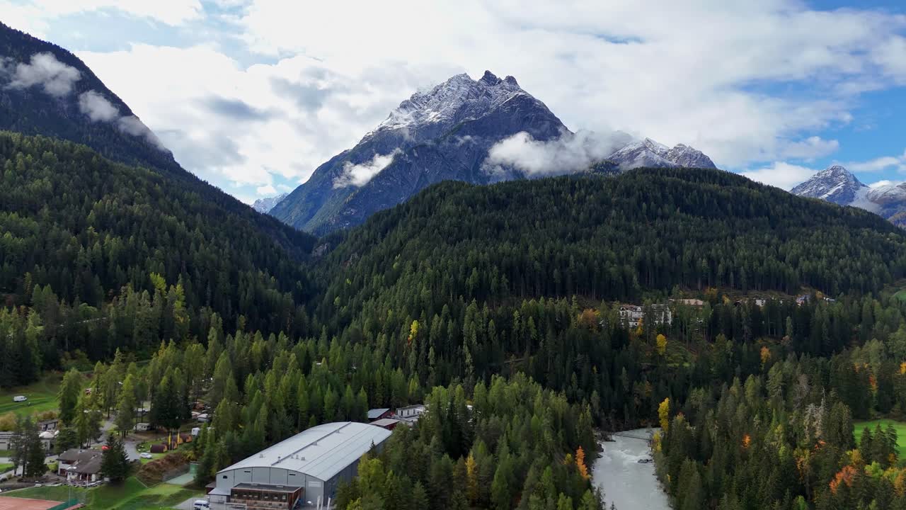 Mountainous forest landscape with a snow-capped peak in Scuol Switzerland under a cloudy sky