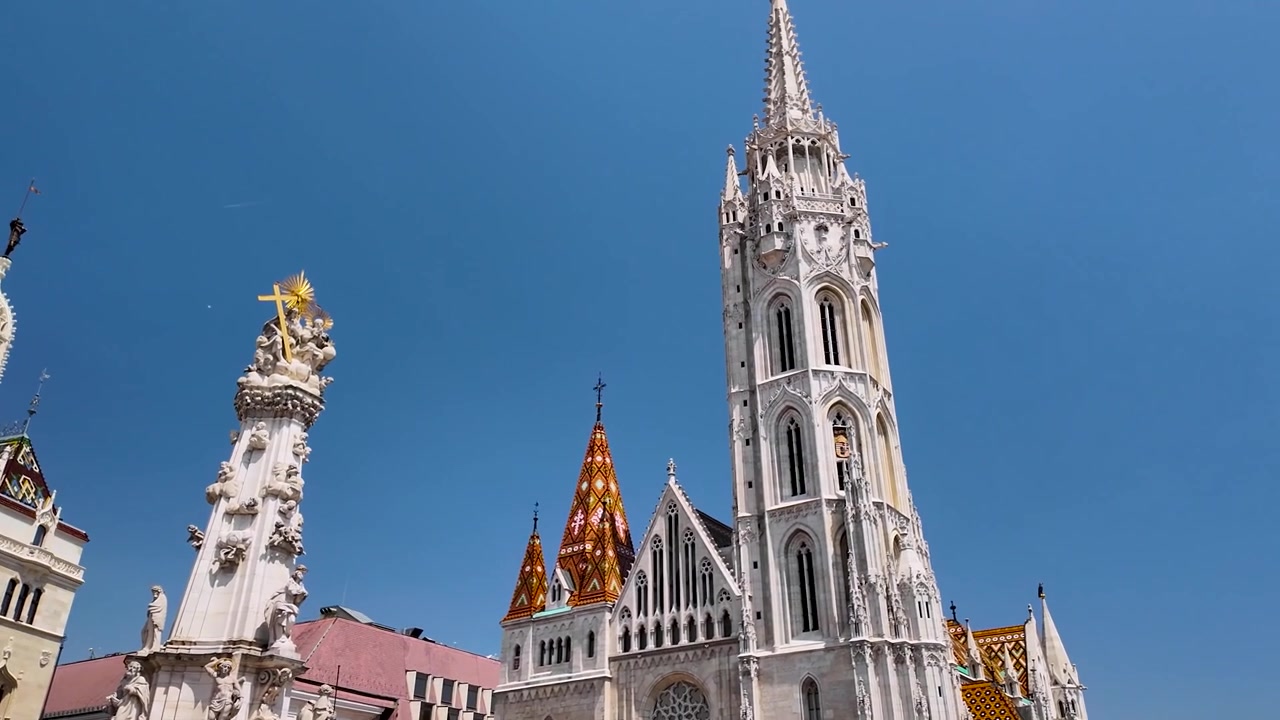Filmatisk sveip over Matthias-kirken og Den hellige treenighetssøylen i Budapest, Ungarn, som viser gotisk arkitektur, utsmykkede detaljer og historiske landemerker i slottsdistriktet