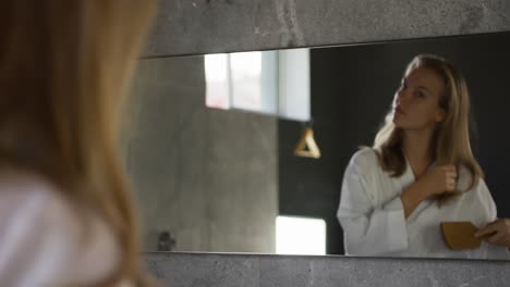 mujer caucásica cepillando el cabello en el hotel