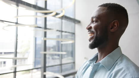 smiling african american man in office, looking out window, feeling positive and confident, copy spa