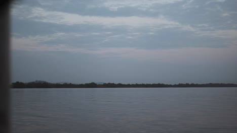 A-tranquil-scene-of-a-forested-lake-or-river-from-the-perspective-of-a-boat