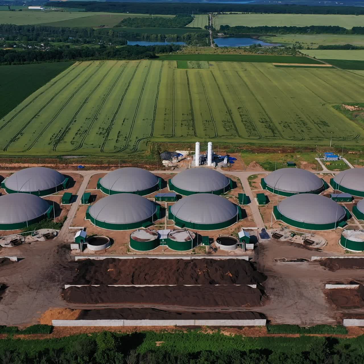 Industrial plant for production bioenergy from waste. Organic fuel tanks from air perspective. Abundant farmlands and forests at the backdrop