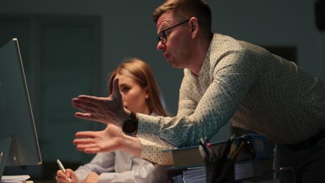 manager and employee working on computer in office late at night