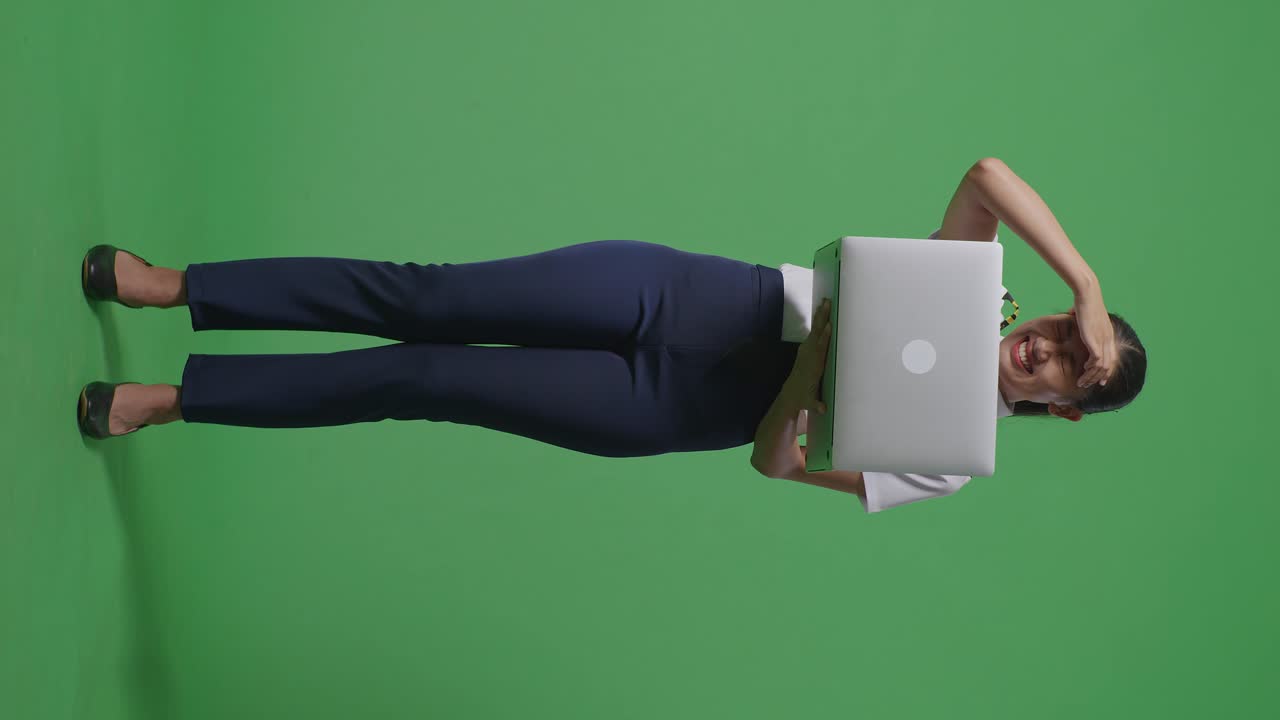 cuerpo lleno de piloto mujer asiática usando una computadora portátil y teniendo un dolor de cabeza mientras estaba de pie en el estudio de fondo de la pantalla verde