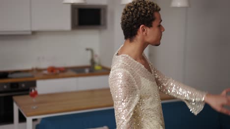 A-man-in-a-dress-admires-himself,-sensually-dancing-on-the-kitchen