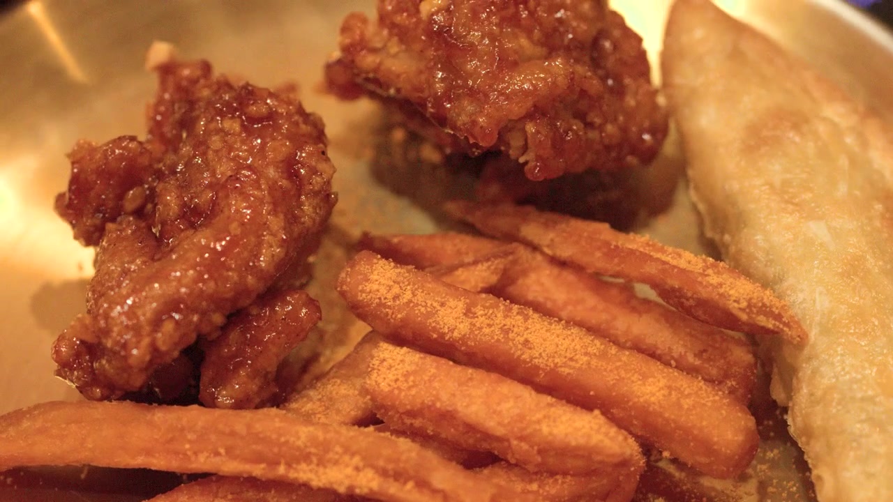 Primo piano di pollo glassato piccante, patatine fritte condite e gnocchi fritti serviti su ottone