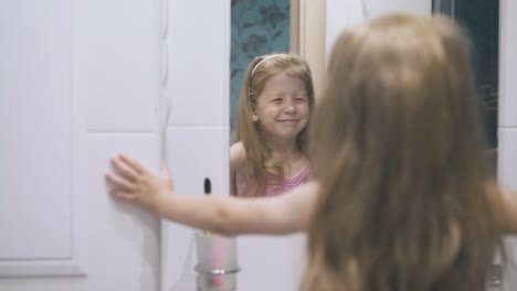 una niña con ojos azules mira el espejo en el baño ligero