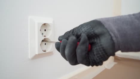 Man-removing-a-plastic-cover-plate-from-a-wall-outlet