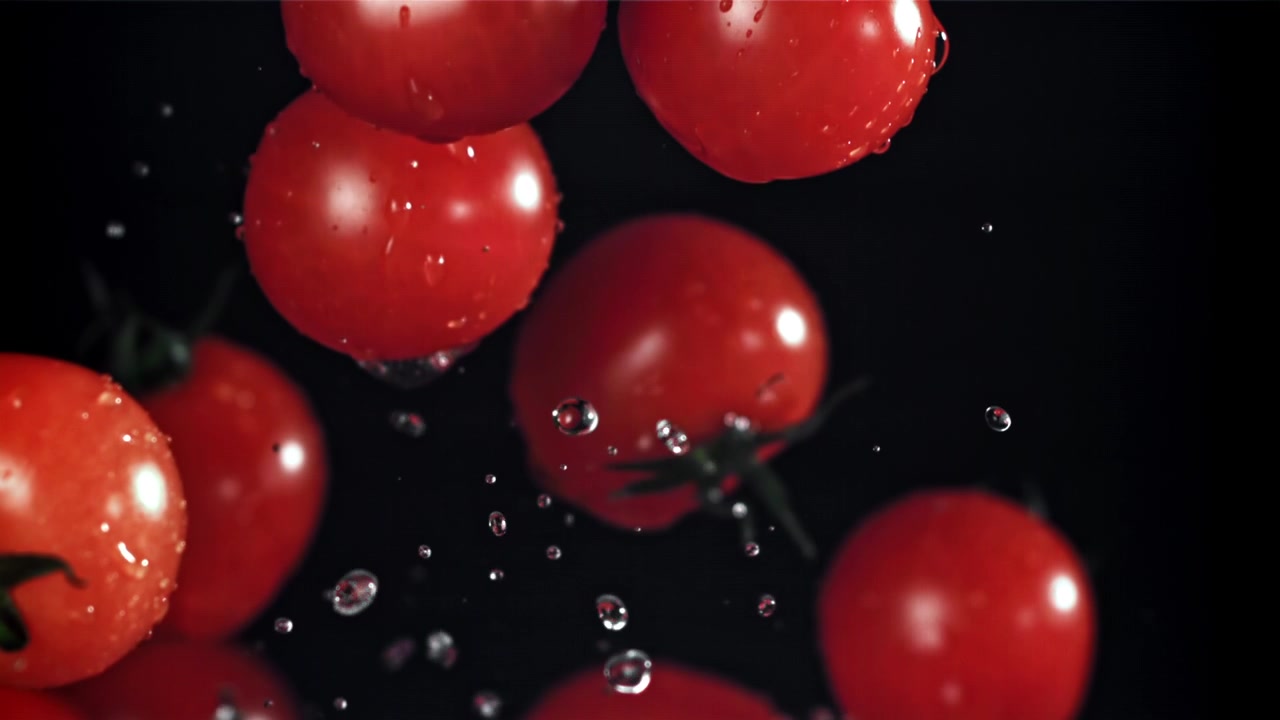 Slow Motion of Fresh Red Cherry Tomatoes Falling with Water Drops