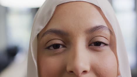 retrato de una mujer de negocios biracial con hijab en la oficina, en cámara lenta.