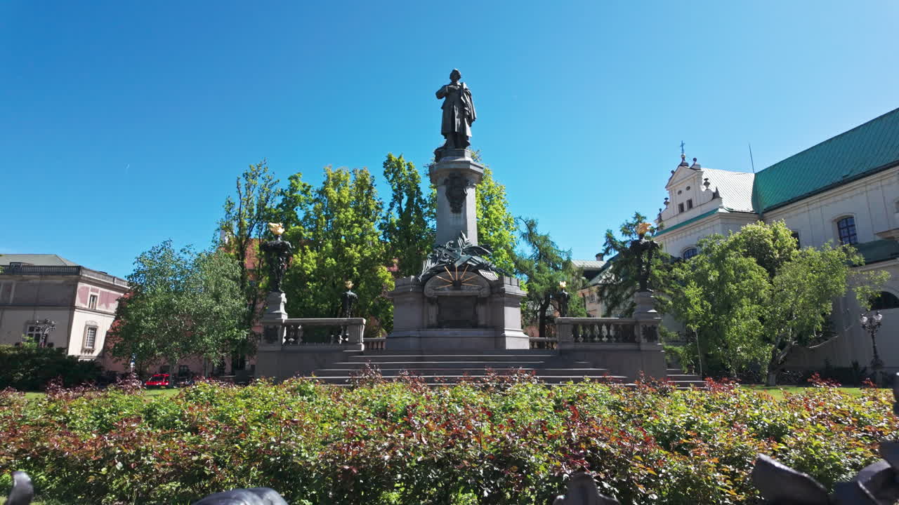 Statue of Adam Mickiewicz in a sunny park, with beautiful greenery and clear skies
