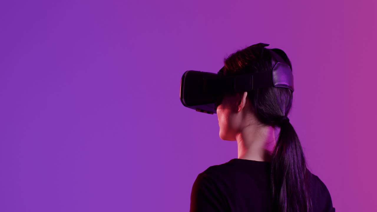 Asian woman using vr headset, touching screen on purple background, copy space, slow motion