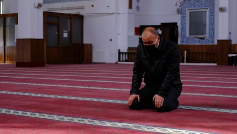 older man wearing a mask turns his head mosque