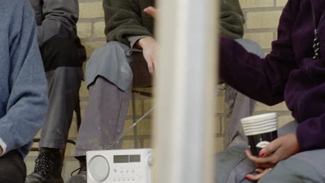 Group-construction-workers-discussing-job-break-talking-holding-coffee-cups-hand-hand-close-up-talk-conversation-drinking-men-discuss-opinion-boss-leadership-listen-listening-radio-analog-play-news