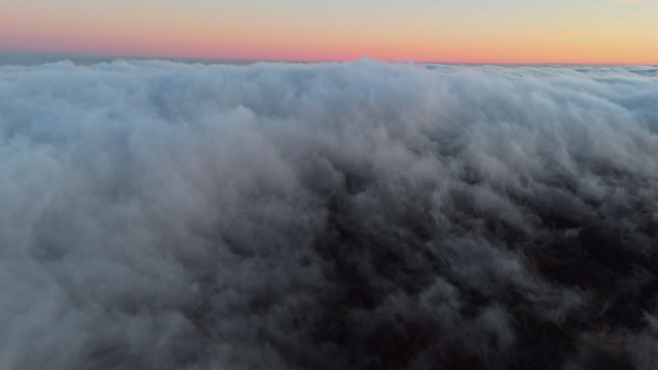Spettacolare vista aerea di nuvole all'alba che fluttuano sopra le scure cime delle montagne