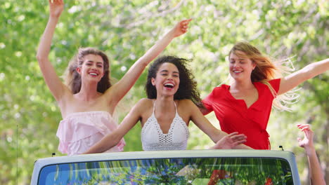 amigas de pie en la parte de atrás de un jeep abierto
