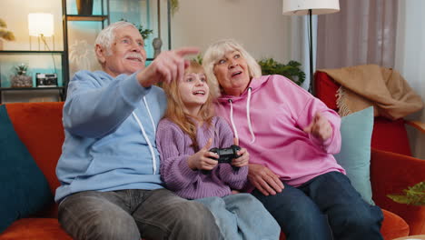 child girl granddaughter grandparents using joystick controller playing console videogame at home