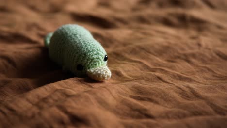 crochet platypus stuffed animal lying on bed