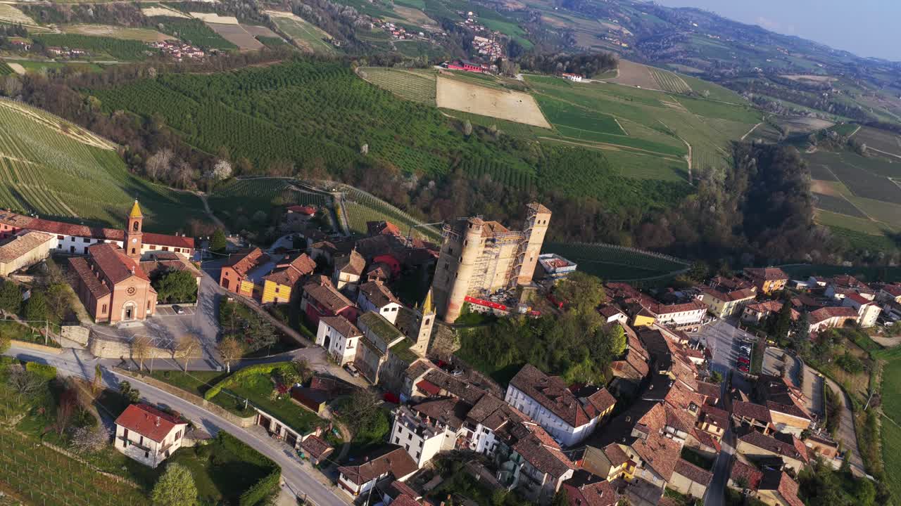Dutch angle aerial shot of Serralunga d'Alba, capturing its iconic castle and surrounding vineyards from a tilted, dynamic perspective, highlighting the dramatic geometry of the Langhe landscape.