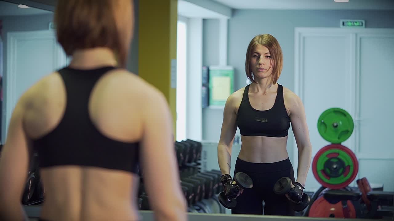 Woman working out with dumbbells in a gym
