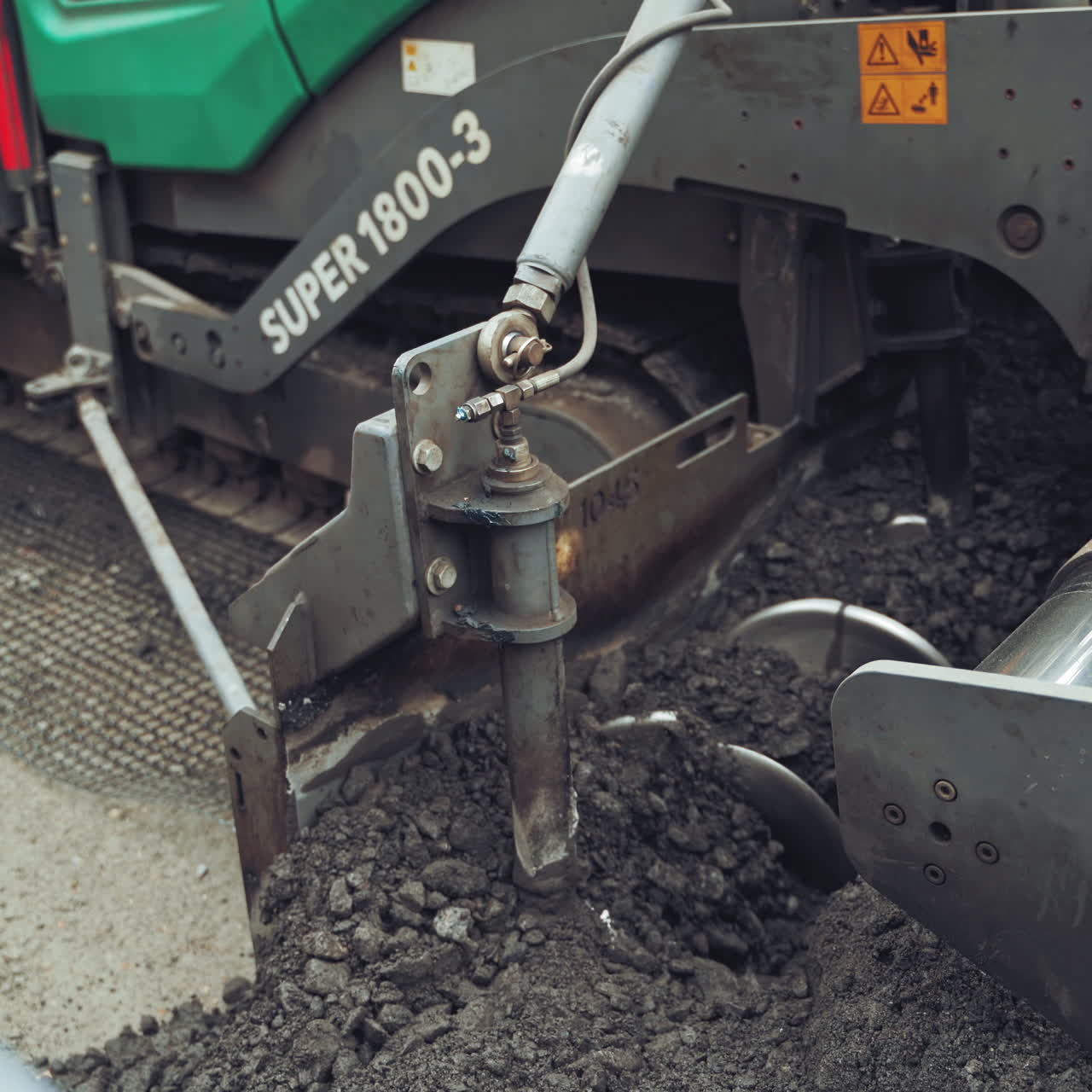 Road construction works during making new asphalt road. Paving machine laying fresh asphalt during road construction. Close-up