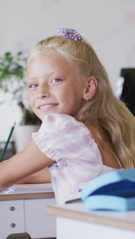 video of happy caucasian girl sitting at desk in classroom