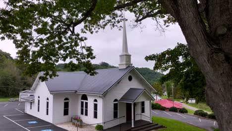 aerial push in to zionville baptist church with tree limbs in foreground in zionville nc, north carolina near boone nc, north carolina