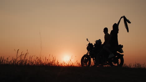 a young romantic couple stands by a motorcycle at sunset 1