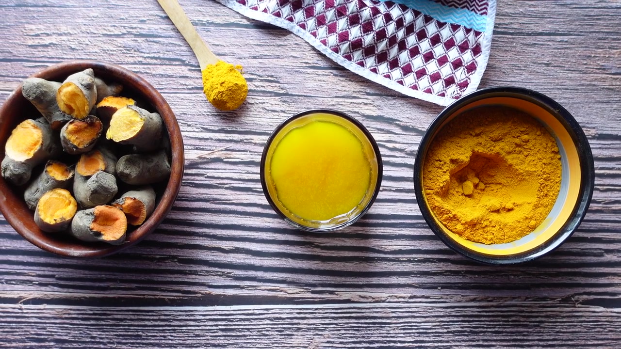 Turmeric Powder, Fresh Roots, and Golden Oil on Wooden Table