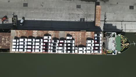 vehicles parked on deck of international cargo carrier vessel on montevideo harbour port, birdseye aerial view