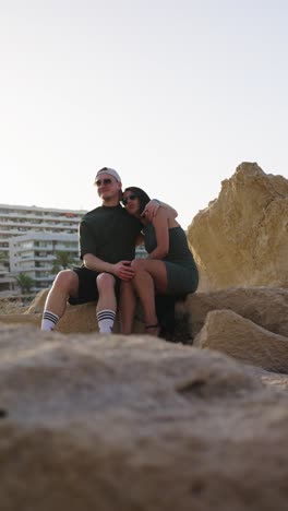 vertical shot of boyfriend hug partner while sit on coastal rock, mallorca