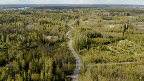 Aerial,-tilt-down,-drone-shot-of-a-car-and-a-bus-on-a-road-in-the-Porvoo-archipelago,-on-a-sunny,-spring-day,-in-the-Saaristo-of-Uusimaa,-Finland